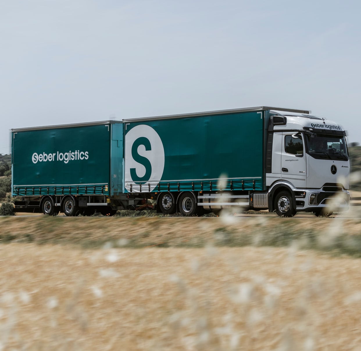 Camió remolc de Seber Logístics per una carretera entre camps