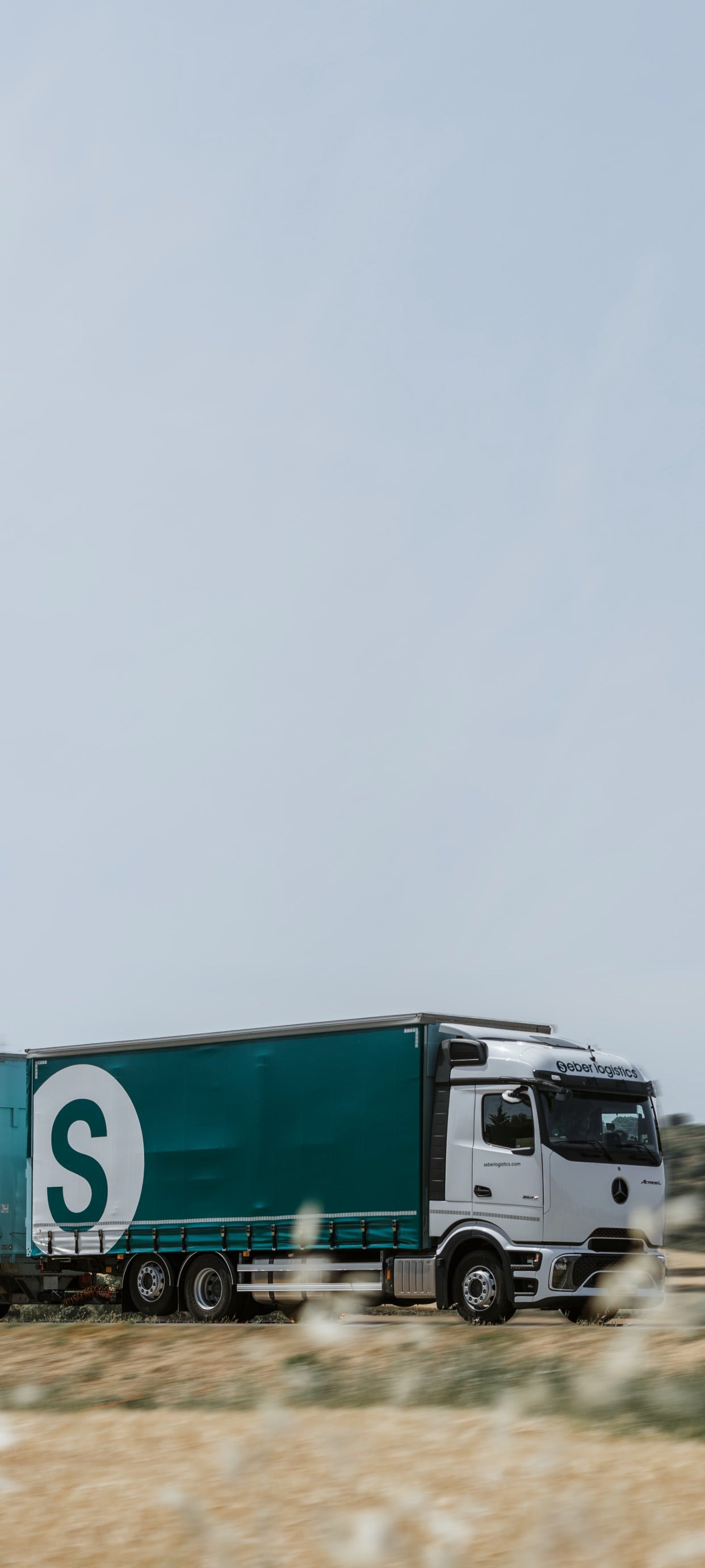 Seber Logístics truck and trailer on a road between fields