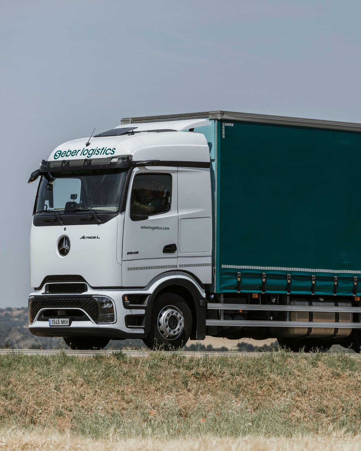 Seber Logístics road train parked beside a field, with the S on the curtain